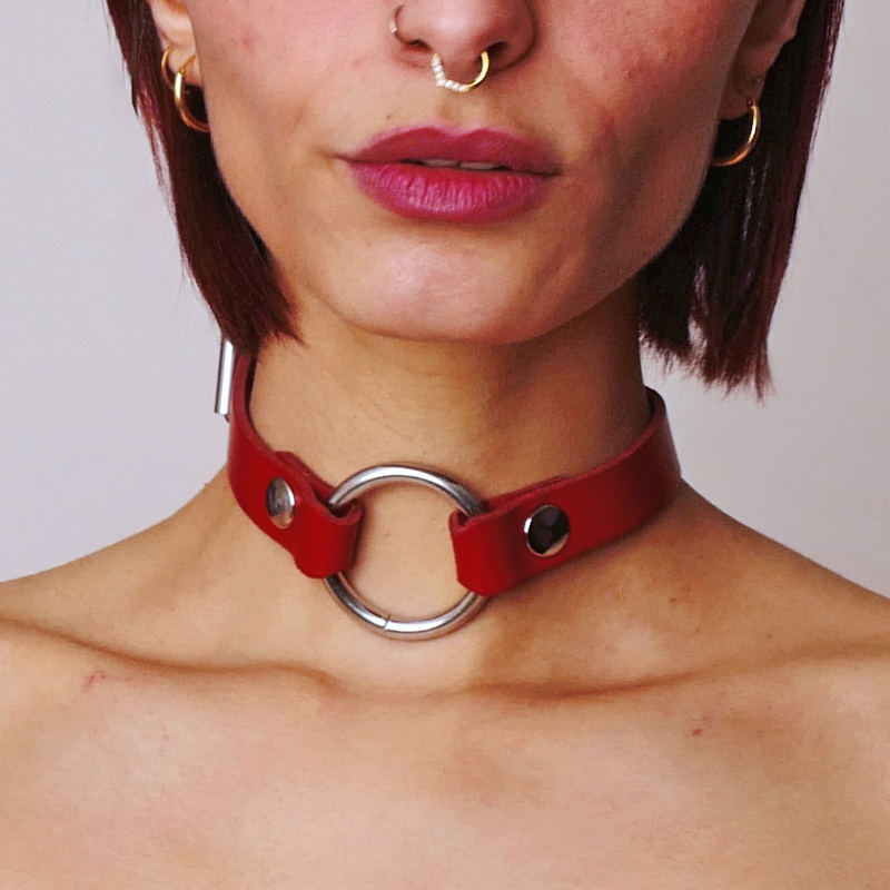 Un collier ras le cou en cuir rouge avec un anneau en acier pour les jeux BDSM.