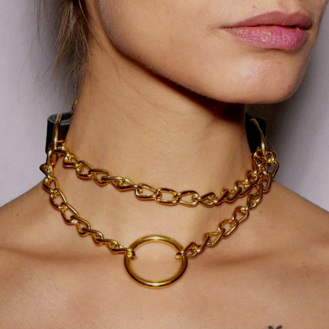 Collier d'étranglement en cuir noir avec chaîne en acier doré. Il sert comme bijou et accessoire BDSM et peut être relié à une laisse.