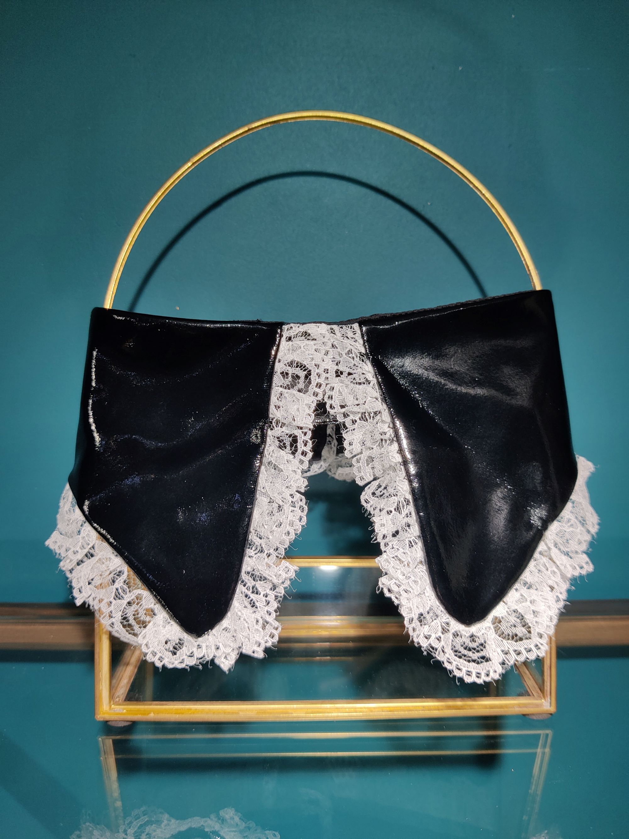 Col de soubrette en vinyle et dentelle, taille unique il se règle grâce à un scratch autour du cou. Fabriqué à la main en France.