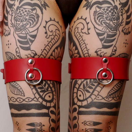 Une paire de menottes pour cuisses en cuir rouge pour intensifier le plaisir lors des jeux de contrainte.