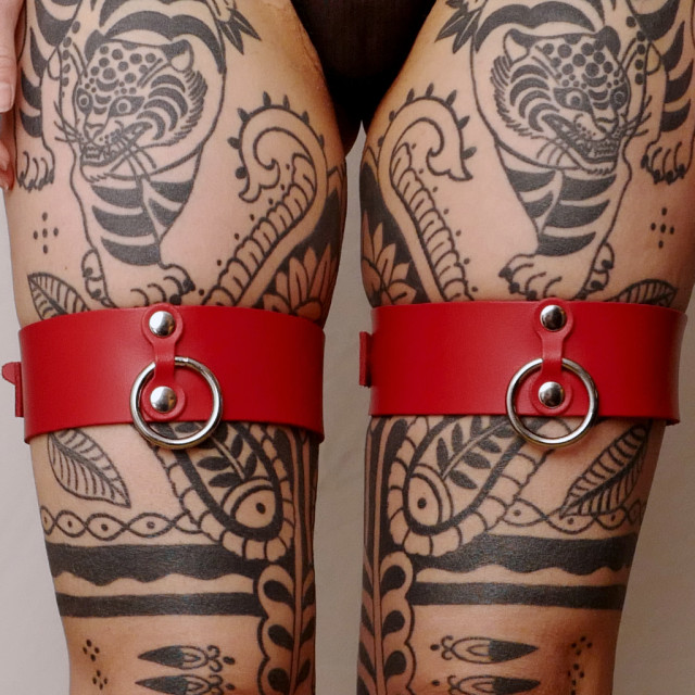 Une paire de menottes pour cuisses en cuir rouge pour intensifier le plaisir lors des jeux de contrainte.
